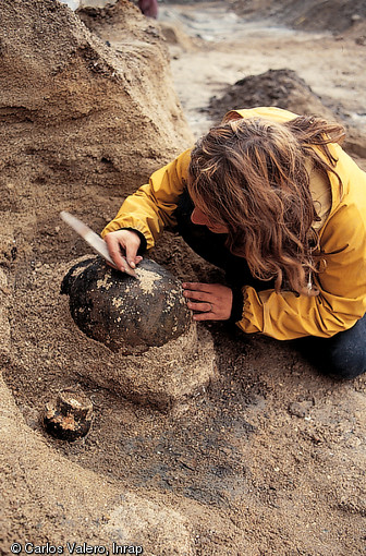 Dégagement d'une des 1 500 poteries néolithiques retrouvées dans un ancien bras de la Seine. Fouille de Paris-Bercy, 1991-1992.