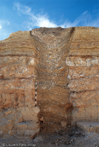 Coupe d'un puits néolithique, qui s'élargit en bas au niveau des chambres d'extraction du silex. Fouille de Jablines (Seine-et-Marne), 1989-1990.  Une fois un banc de silex épuisé, le puits était comblé avec des déblais du creusement d'un nouveau puits. Dans ces déblais on retrouve des restes des outils d'extraction et du travail de débitage des haches de silex.  