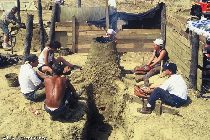 Reconstitution expérimentale de bas fourneaux protohistoriques organisée en juillet 1987 à la suite de la découverte de nombreux bas fourneaux sur l'emprise de l'autoroute A28 dans le secteur du Mans en 1996-1997.    La mise en chauffe du bas fourneau est activée à l'aide d'une batterie de soufflets. 