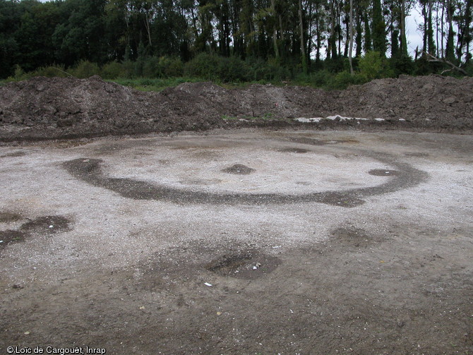 Fossé d'enclos circulaire appartenant à un monument funéraire de la nécropole  du Petit Moulin  (Yonne) datant du Bronze final, 2004.  Le contour du fossé rempli de terre se détache du substrat graveleux plus clair qui l'entoure.   