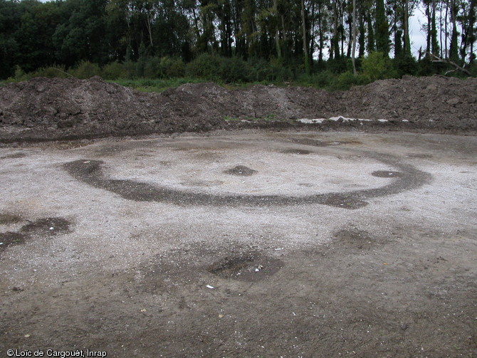 Fossé d'enclos circulaire appartenant à un monument funéraire de la nécropole  du Petit Moulin  (Yonne) datant du Bronze final, 2004.  Le contour du fossé rempli de terre se détache du substrat graveleux plus clair qui l'entoure.   