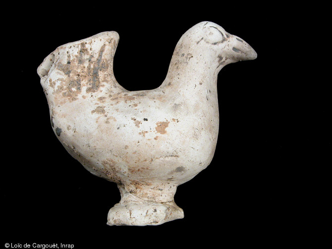 Figurine en terre cuite blanche représentant une poule, nécropole gallo-romaine de Pont-l’Évêque, Autun (Saône-et-Loire), 2004.  Il s'agit d'une représentation zoomorphe très courante, ici retrouvée hors contexte. On pense que ce type d'objet était destiné à être brûlé sur le bûcher funéraire. 