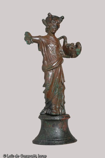 Tutela (divinité protectrice) en bronze, Gonesse (Val-d'Oise), 2004.  La déesse est coiffée d'une tour crénelée, symbole de la ville qu'elle protège. Elle tient dans sa main gauche une corne d'abondance et dans sa main droite un attribut aujourd'hui disparu, peut-être un gouvernail. Ses yeux sont en argent.