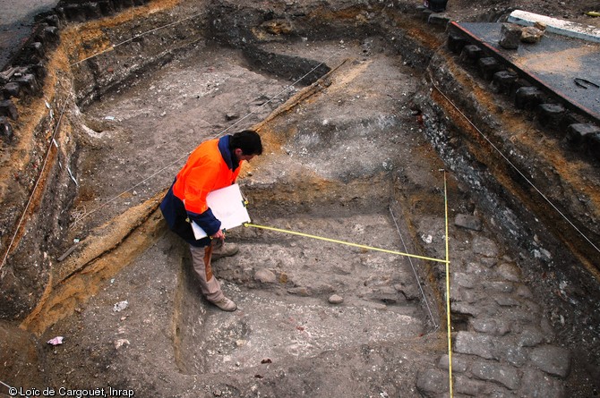 Relevé des vestiges mis au jour dans une tranchée de diagnostic réalisée près de la porte de Mars à Reims entre juillet 2007 et novembre 2008. L'opération a révélé un tronçon du cardo (axe nord-sud de la ville) passant sous l'arc principal et présentant un état ancien daté du courant du IIe s. de notre ère et un récent contemporain à l'aménagement de la porte de Mars.
