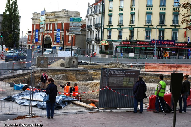 Fouille place de la République à Reims (Marne), 2007-2008.  Les passants peuvent voir le travail des archéologues et prendre connaissance des premières informations livrées par la fouille sur un panneau mis à leur disposition. 