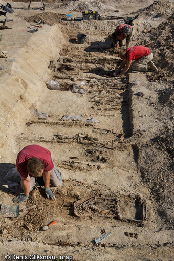 Fouille en cours d'une sépulture multiple découverte dans un cimetière militaire allemand de fortune de la Grande Guerre dans le village de Boult-sur-Suippe, Marne (2016). Selon la motalité journalière, les sépultures sont individuelles, doubles ou multiples, et peuvent contenir jusqu'à douze individus.