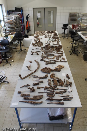 Vue d’ensemble du mobilier métallique antique en cours de traitement dans la salle de lavage du centre archéologique de Dijon et découvert dans une ferme à Saint-Clément, Yonne (2016).   La mise au jour d’ensembles si complets et en tel état de conservation est d’une grande rareté. Si le métal a pu se conserver durant près de 2000 ans en milieu clos, son exposition à l’air  et à la lumière accélère ensuite sa détérioration. Afin d’éviter leur inéluctable dégradation, les objets en métal doivent être stabilisés et restaurés. 