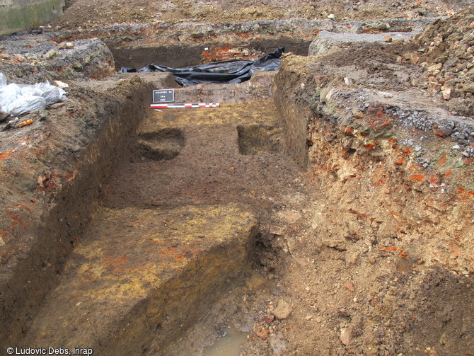 Sols en terre battue d’une maison de la fin du 14e siècle découverte à Orchies (Nord), 2013. Les tranchées ont livré les restes de deux ou trois bâtiments aux sols de terre battue et aux murs sur solins de grès ou sablières basses en bois.