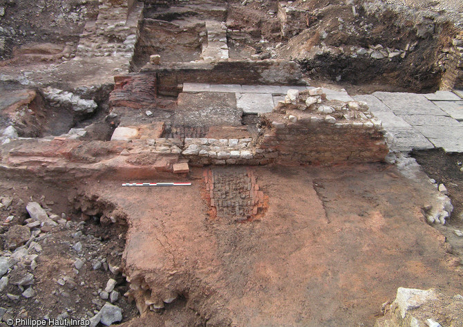 Une partie des thermes publics romains de Besançon (Doubs), fouillés en 2005.  Au premier plan, l’area (sol en béton de tuileau) constitue la partie inférieure du dispositif de chauffage par le sol (hypocauste). Le foyer, construit en briques, relie la pièce chauffée au local de chauffe (où le feu est alimenté), délimité par le sol dallé.