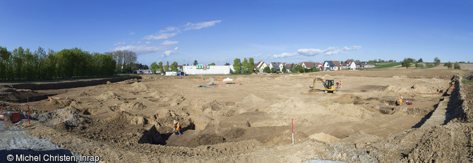 Vue générale du chantier de fouille néolithique d'Achenheim (Bas-Rhin), 2016. Plus de 300 silos ont été découverts, à l'intérieur d'une vaste enceinte matérialisée par un puissant fossé, dont les entrées sont protégées par des sortes de bastions. Ce dispositif défensif évoque des temps troublés, qui au Néolithique moyen forcent les populations à se protéger.