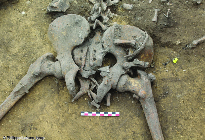 Détail de la fosse 124 sur le site néolithique d'Achenheim (Bas-Rhin), 2016. Armature de flèche retrouvée dans la région du bassin d'un homme adulte. Cette fosse est un vaste silo de près de 2,5 m de diamètre dans lequel ont été abandonnés six individus présentant tous des traces de nombreuses fractures. Ce dépôt de cadavres est constitué en un temps, et évoque une même tuerie, un même conflit.
