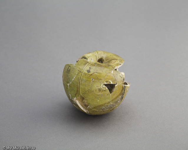 Objet décoratif en céramique à revêtement glaçuré, en forme de pomme, 1er siècle de notre ère, hauteur 7 cm, découvert sur le site du lycée Saint-Euverte à Orléans (Loiret). Cet objet, reposant sur un fond plat de très petit diamètre, est percé de 3 trous en son sommet. On en ignore la fonction. La production de céramique à glaçure plombifère, caractérisée par une couverte vitrifiée de couleur variant du jaune au vert, a été relativement limitée au cours de l'Antiquité. 