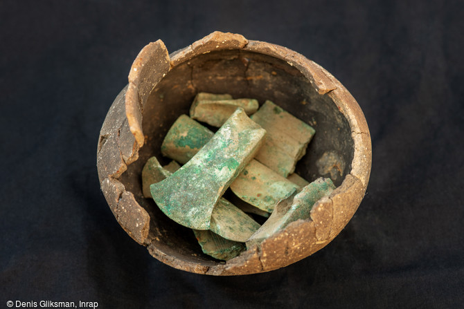   Restitution de l'emplacement des objets métalliques du Bronze final dans un rare dépôt mis au jour dans un secteur dépourvu d'habitat sur le Mont Castel à Port-en-Bessin (Calvados). Dans cette poterie étaient associés fragments d'épée, différents types de hache (dont plusieurs à ailerons), fragment de lance etc...     