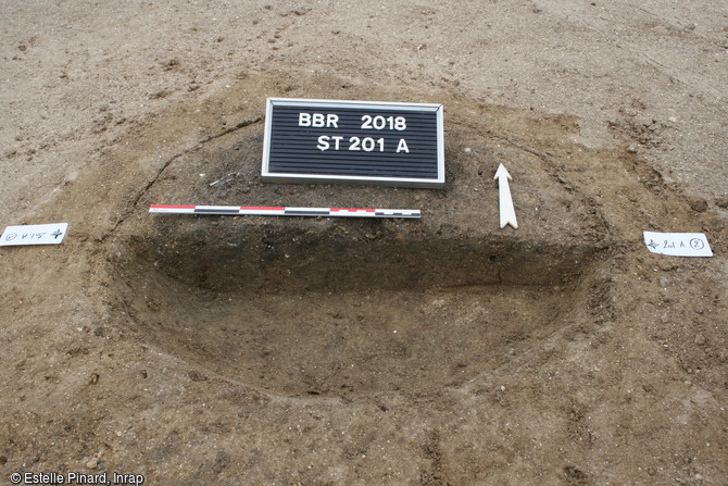 Dépôt des restes osseux concassés, mêlés aux résidus du bûcher dans une fosse sur le site de Bitry (Oise), premier âge du Fer. 