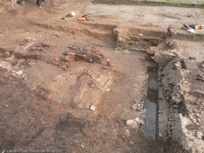 Fouille des thermes gallo-romains à Portbail (Manche). A droite : égout servant à l'évacuation de l'eau des thermes (piscines, baignoires...) ; au premier plan chaufferie ; à l'arrière-plan : pilettes d'hypocauste.