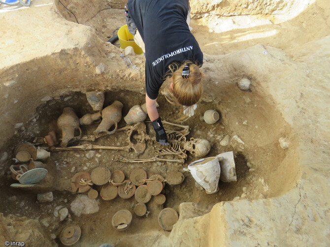 Une anthropologue de l'Inrap travaille au dégagement de la sépulture  de culture étrusque (IVe siècle av. notre ère) à Aléria (Haute-Corse). Un riche mobilier est entreposé autour de la défunte. 