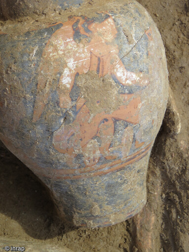 Oenochoé de production d'Etrurie datant du IVe siècle avant notre ère découvert à Aléria (Haute-Corse) dans une chambre funéraire étrusque en hypogée. La peinture de cette oenochoé représente un personnage ailé accompagné d'un animal quadrupède non défini.Des rehauts blancs se distinguent participant au caractère stylistique du dessin attribué à la culture étrusque, dont la fragilité a nécessité l'intervention in situ des restauratrices-conservatrices. 