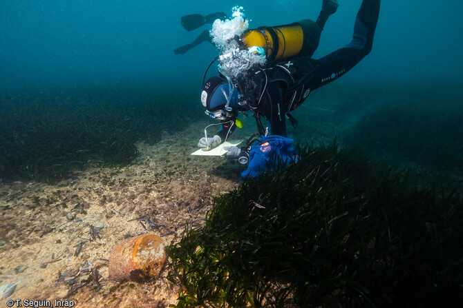 Un plongeur archéologue prend des notes après avoir découvert en prospection des vestiges mobiliers.