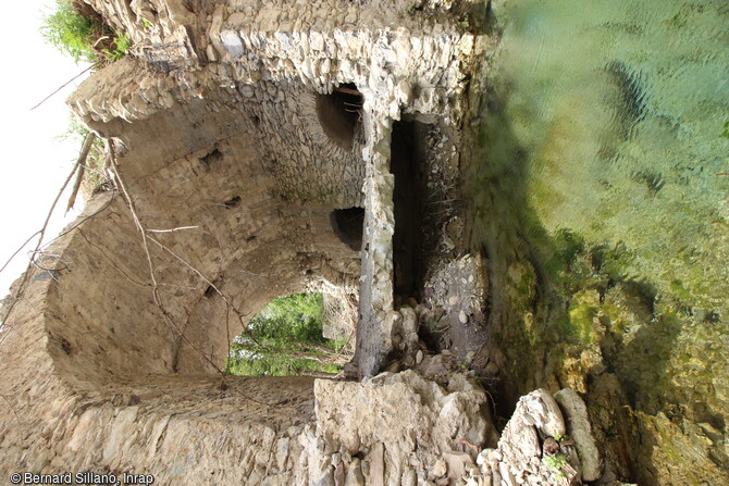 Le couvrement du moulin bas, ancien moulin à huile, et une arche du pont, en cours de fouille en 2022. Au premier plan, la nappe phréatique dans la fosse creusée par la crue de la vallée de la Roya à Saorge (Alpes-Maritimes)