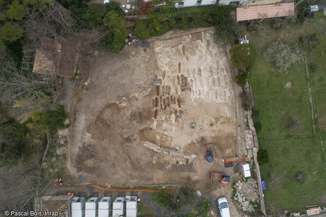 Vue aérienne de la moitié nord du site de fouille du quartier de Saint-Ferréol à Uzès (Gard). L'emprise du site a permis l'étude de près de 200 sépultures, orientés ouest/est, implantées en rangées et quasi systématiquement installées dans le rocher.