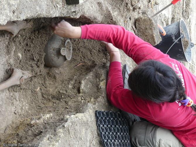 Sépulture en cours de fouille dans le cimetière rupestre (VIIe-XIIe siècle) du quartier de Saint-Ferréol à Uzès (Gard). Un pot en céramique est déposé au pied du défunt. Une trentaine de pots globulaires, à usage domestique et de fabrication locale a été exhumée des tombes. Contenant des cendres, de l'encens ou de l'eau banite, ils recevaient une pierre en guise de bouchon afin de protéger le contenu au moment du rebouchage de la tombe. 