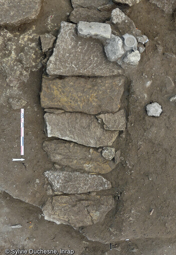 Sépulture avec sa couverture et son pot en céramique déposé et calé par des pierres à la tête du défunt mise au jour dans le cimetière rupestre (VIIe-XIIe siècle) du quartier de Saint-Ferréol à Uzès (Gard). Une trentaine de pots globulaires a été exhumée des tombes. Ces pots étaient déposés soit en contact du défunt, soit en couverture, soit encore au-dessus dans la fosse comblée de terre. 