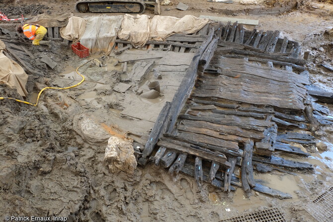 Vue générale du bateau en cours de nettoyage à Villenave-d'Ornon (Gironde) en 2022. Enfouie dans l'ancien lit envasé du ruisseau l'Estey du Lugan, l'épave est conservée sur 12 m de long mais sa taille initiale peut être estimée à une quinzaine de mètres. les datations radiocarbones attribuent ce bateau aux VIIe-VIIIe siècles. 