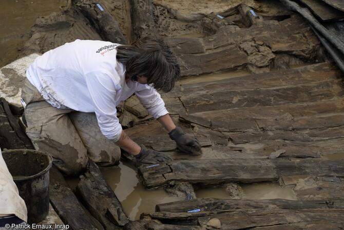 Nettoyage à l'éponge du plancher avant, de l'épave du bateau du haut Moyen Âge découverte à Villenave-d'Ornon (Gironde) en 2022.