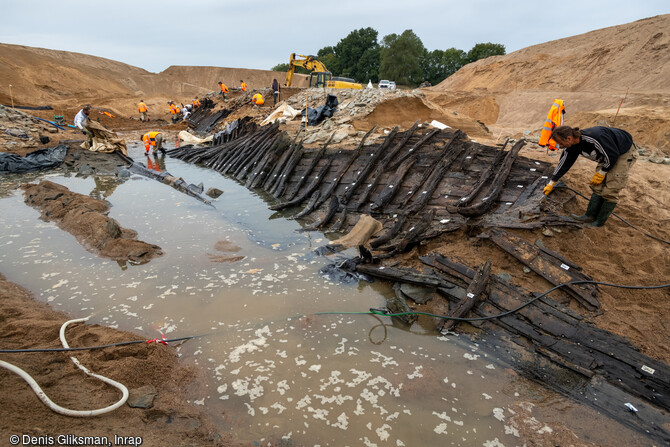 Arrosage des épaves des XVIIe-XVIIIe siècles mises au jour de l'île Coton, Ancenis (Loire-Atlantique) en 2022. Le bois doit être maintenu humide pour des questions de conservation. Ces bateaux en chêne avaient une étanchéité assurée par un système de  plâtrage  (intercalage de mousse végétale entre les planches). 