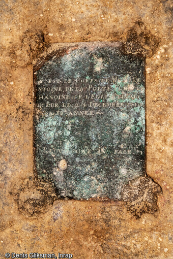 Épitaphe en latin gravée sur une plaque de bronze, et scellée sur le couvercle du sarcophage découvert dans le transept de Notre-Dame de Paris. Elle a livré le nom du défunt, mais aussi sa fonction : Antoine de La Porte (1627-1710) surnommé le  Chanoine jubilé, pour avoir occupé ses fonctions à Notre-Dame de Paris durant plus de 50 ans. Riche prélat, il contribua financièrement aux travaux de réaménagement du chœur souhaité par Louis XIII. 