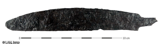 Couteau médiéval à dos courbe et tranchant droit provenant d'une cabane médiévale sur le site d'Algolsheim (Haut-Rhin). La soie du manche est partiellement observée. L. lame : 12.9 cm - l. max. 2.3 cm.