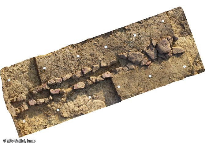 Orthophotographie du dalot retrouvé sur le site de Drulingen (Bas-Rhin). Orientée est-ouest, cette structure linéaire est construite en pierres sèches, avec des moellons de grès rose alignés, disposés sur une assise et qui reposent directement sur le substrat. Sa couverture est constituée de dalles en grès rose posées à plat. Ce type de structure, utilisé pour l’arrivée d’eau et l’évacuationdu trop-plein, est assez commune à l’époque romaine dans le secteur.