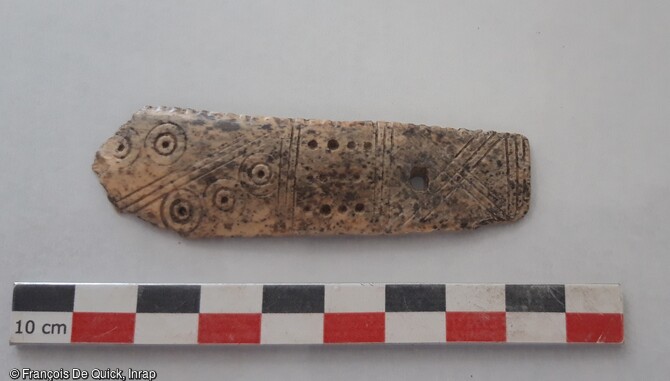 Fragment d'un peigne en os d'époque carolingienne, avec un décor d'ocelles découvert à Onnaing (Nord). 
