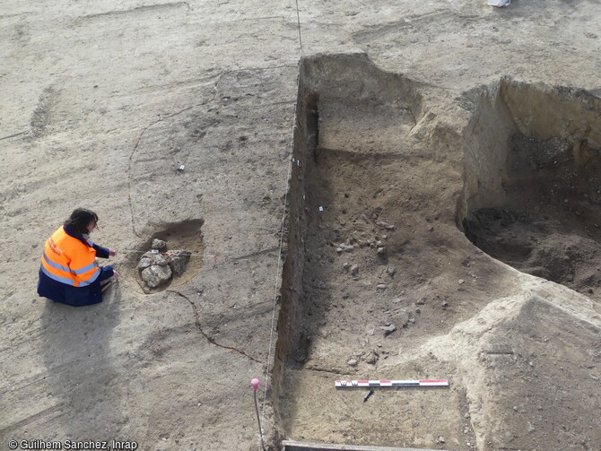 Fosse du Néolithique final en cours de fouille à Béziers (Hérault) en 2023. A gauche, les pierres signalent la présence d'un inhumation. Plusieurs superstructures (de 5 m de circonférence pour une profondeur de 1,30 m conservé) ont été creusées dans le but d'extraire de grandes quantités de terre. 