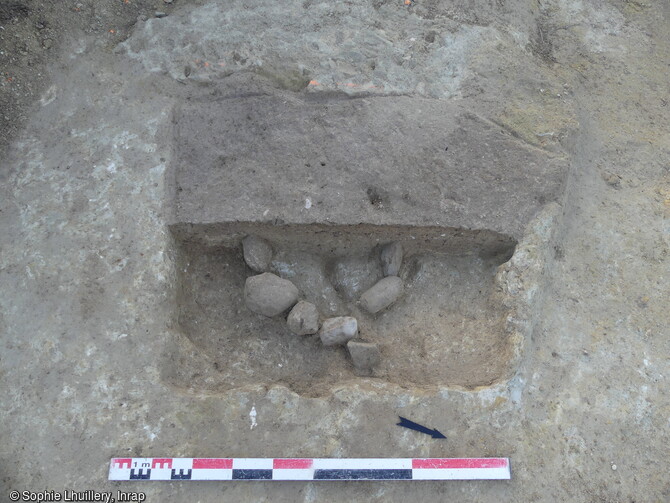 Vue d'une fosse de plantation antique avec un calage en pierre de la motte centrale sur site des Fangasses à Béziers (Hérault) en 2023. Dans l'Antiquité, le secteur témoigne d'activités agraires. Plusieurs fosses de plantation dessinent une trame qui doit être certainement en lien avec le domaine (villa) situé à proximité et le passage de la Via Domitia à moins de 100 m. 