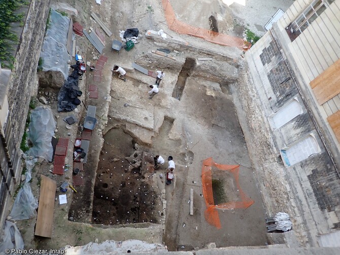 Vue générale de la fouille de l'École des Mines de Paris. A partir du 1er siècle de notre ère, Lutèce se développe sur la rive gauche de la Seine. La fouille en cours se situe aux marges de la cité du Haut-Empire (Ier-IIIe siècles) et a révélé une activité artisanale liée au travail du fer. Elle a mis au jour des fondations en pierre antiques, une aire de circulation, une vaste fosse (citerne ou réceptacle d'eau) transformée en dépotoir et un secteur qui peut être interprété comme une forge.