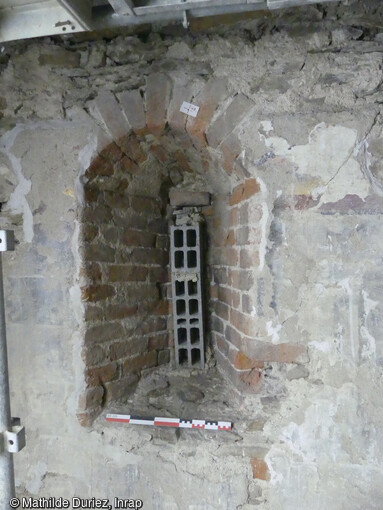 Baie en brique, antérieure aux enduits peints - mur gouttereau nord - intérieur. La première phase de construction de l'église du XIVe siècle de l'ancienne chartreuse de Sainte-Croix-en-Jaretz (Loire) correspond à l'édification d'une vaste nef quadrangulaire éclairée depuis le nord par plusieurs fenêtres construites en briques.