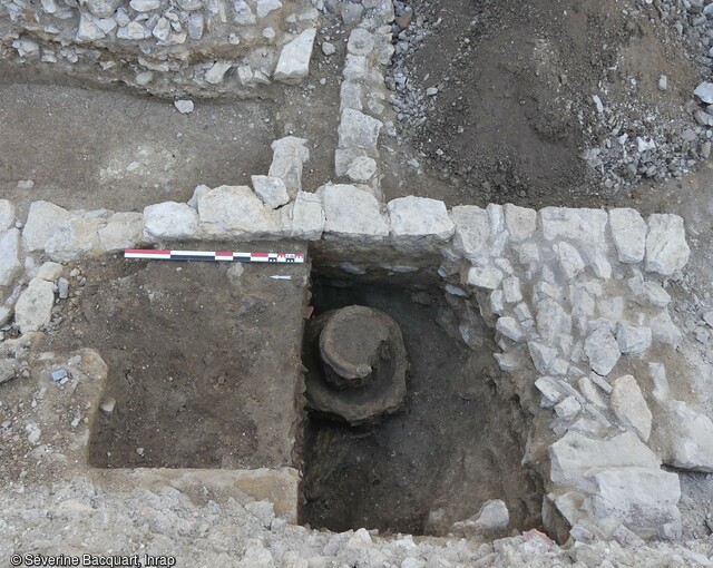 Vue de la fosse de coulée de cloches en cours de fouille à Baume-les-Dames (Doubs). Cette fosse a été aménagée dans le courant du 13e siècle, sur le tracé du mur occidental de l'église antérieure. Au sein de cette fosse, dont le comblement était riche en résidus d'alliage cuivreux, a été observée la base de deux noyaux de cloche en argile jaune, de 0,51 et 0,80 m de diamètre. 