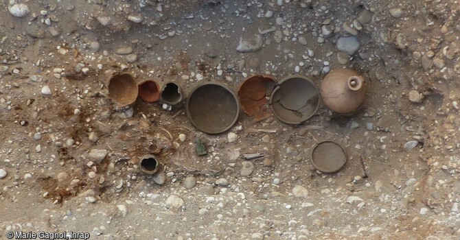 Sépulture d'un enfant entre 1 et 6 ans inhumé dans un cercueil cloué avec des dépôts de neufs vases en céramique, deux monnaies, une fibule, un bracelet et un dépôt alimentaire de coq domestique. Mis au jour dans l'ensemble funéraire antique de Saint-Vulbas (Ain)