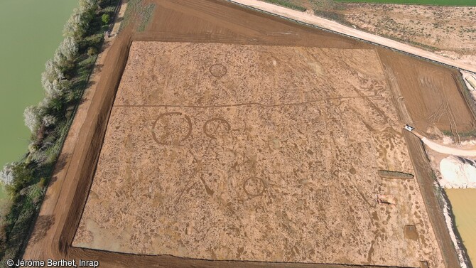 Vue générale de la nécropole après décapage à Marliens (Côte-d'Or). cette nécropole datant de 1500-1300 av. notre ère est composée d'enclos circulaires. L'acidité du sol n'a pas permis la conservation des os non brûlés, cependant des restes d'inhumations et un bûcher funéraire ont été identifiés dans les fossés du plus grand enclos.  