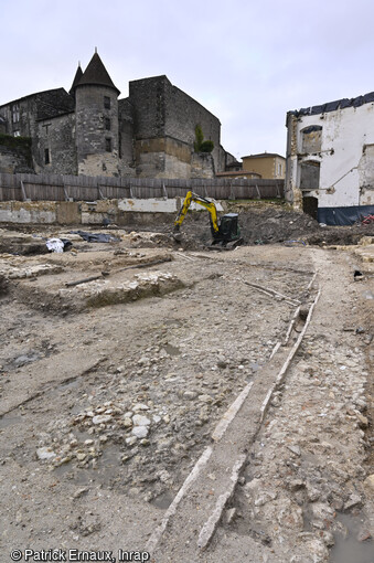 Voirie et caniveaux (XVe-XVIe siècles) en cours de fouille avec le château en arrière-plan à Cognac (Charente)