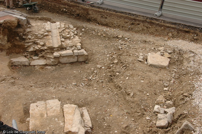 Détail du rempart du XVIe s., vu de l’extérieur, avec une rigole d'évacuation en pierre taillée prise dans la maçonnerie, fouille de la place de la République à Dijon (Côte-d'Or), 2010.  Du fossé remblayé émergent, au premier plan, les maçonneries d'une pile de l'ancien pont de la porte St Nicolas.