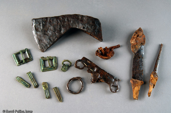 Ensemble d'objets métalliques (hache en fer, boucles en bronze) mis au jour en 2006 dans une des tombes de la nécropole de Saint-Marcel (Morbihan), Ve s. de notre ère.  Les objets de parure se rattachent d'un point de vue stylistique à des productions du sud-est de l'Angleterre imprégnées des interactions entre monde romain tardif et culture germanique. 