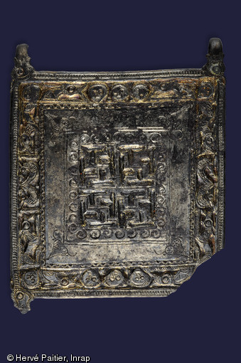 Plaque avec quatre agrafes de fixation gravée d'animaux, de svastikas et de visages. Elle ornait le vêtement de l'un des défunts découvert dans l'une des sépultures de la nécropole de Saint-Marcel (Morbihan), Ve s. de notre ère, 2006.