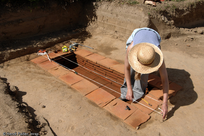 Sépulture à inhumation d’un enfant (8 - 9 ans) dans un caveau en briques (longueur 2,40 m, largeur 1 m), IIe-IIIe s. de notre ère, Neuville-sur-Sarthe (Sarthe), 2010.  La mise au jour d’une telle tombe dans l’enceinte sacrée d’un temple gallo-romain pose la question de leur éventuelle contemporanéité, en effet il est de règle à l’époque gallo-romaine de séparer ce qui est « pur » (les temples) de ce qui est « impur » (les inhumations par exemple).