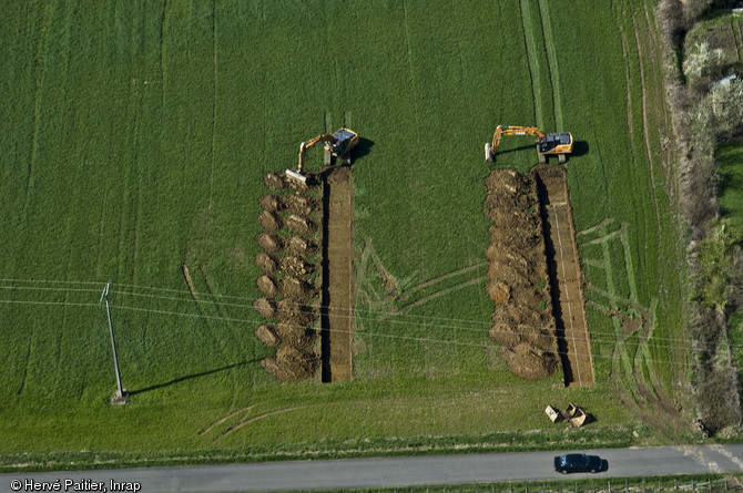 Tranchées de sondages archéologiques réalisées dans le cadre de la construction de la LGV Bretagne - Pays de la Loire, 2010.  Entre 5 et 10 % de la surface concernée par l'aménagement est ainsi ouverte, ce qui permet de localiser et d'évaluer l'importance de sites archéologiques menacés de destruction.