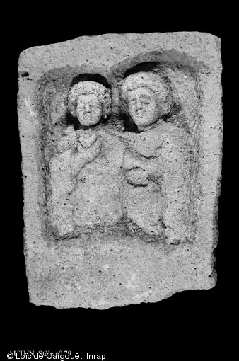Stèle funéraire gallo-romaine en granit (hauteur 74 cm, largeur 52 cm), nécropole de Pont-L'Évêque, Autun (Saône-et-Loire), 2004.  La stèle représente un couple debout dans une niche à double cintre. Le bras droit de l'époux passe derrière le cou de sa compagne pour lui poser la main sur l'épaule. L'épouse tient une fleur dans sa main droite. 