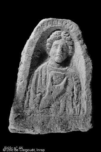 Stèle funéraire gallo-romaine en grès (hauteur 70 cm, largeur 51 cm), première moitié du IIe s. de notre ère, nécropole de Pont-l'Évêque, Autun (Saône-et-Loire), 2004.  Le nom de la défunte est inscrit en haut de la stèle : Valer(i)a. De part et d'autre de son visage on peut reconnaître les lettres D et M, correspondant à Diis Manibus ( Aux dieux mânes ), formule appelant à la bienveillance des ancêtres. 