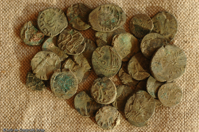 Détail de quelques pièces du dépôt monétaire du faubourg d'Arroux à Autun (Saône-et-Loire), fin du IIIe s. de notre ère, 2010.  Le dépôt se compose de plus de 100 000 petites pièces, toutes en bronze, destinées à la refonte. Ce sont des émissions non-officielles produites par des particuliers qui imitent le monnayage officiel de l'Empire. 