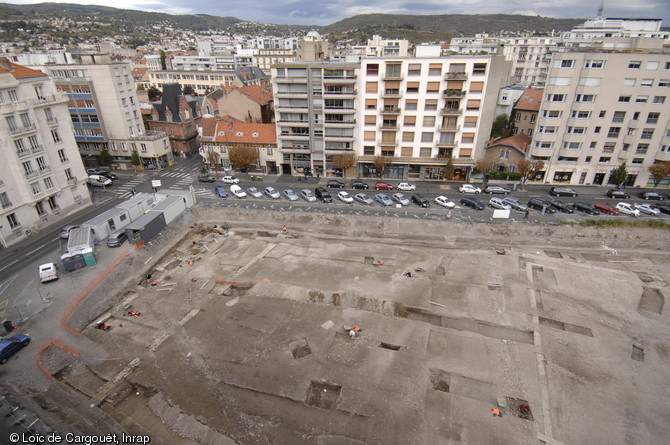 Vue générale de la fouille du Carré-Jaude (Clermont-Ferrand) où a été identifié le secteur monumental de la ville d'Augustonemetum du milieu du IIe s. de notre ère, 1995.  La fouille a révélée plusieurs édifices monumentaux s'organisant autour d'une esplanande et au sud un vaste bâtiment à portique adossé à des ateliers et des boutiques interprété comme un marché couvert. 